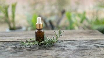 The bottle of rosemay oil with fresh rosemary on wood table background, healthy herbal oil concept photo