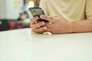 relajado joven asiático hombre utilizando inteligente teléfono gasto hora comprobación Noticias social medios de comunicación. foto