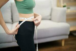 asiático sano mujer dieta peso pérdida. Delgado mujer medición cintura con medida cinta después dieta a hogar peso control. foto