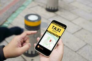 Man in downtown city street ordering taxi using smart phone app Booking taxi using application online on smart phone photo