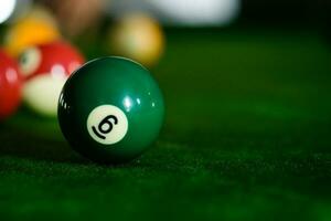 Man's hand and Cue arm playing snooker game or preparing aiming to shoot pool balls on a green billiard table. Colorful snooker balls on green frieze. photo