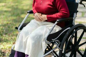 Nursing home. Young caregiver helping senior woman in wheelchair. photo