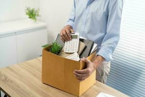 Business man sending resignation letter and packing Stuff Resign Depress or carrying business cardboard box by desk in office. Change of job or fired from company photo