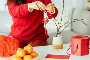 Asian Woman decorated house for Chinese New Year Celebrations. putting traditional pendant to the Chinese Lunar New Year for good luck. Chinese word means blessing photo