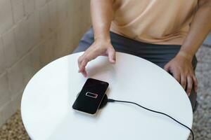 Charging mobile phone battery with wireless charging device in the table. Smartphone charging on a charging pad. Mobile phone near wireless charger Modern lifestyle technology concept. photo