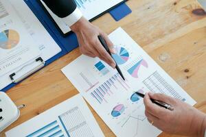 Businessman analyzing investment charts and pressing calculator buttons over documents. Accounting Concept. photo