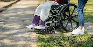 Nursing home. Young caregiver helping senior woman in wheelchair. photo