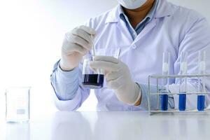 Science innovative Male medical or scientific laboratory researcher performs tests with blue liquid in laboratory. equipment science experiments technology Coronavirus Covid-19 vaccine research photo