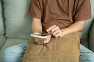 Relaxed young asian man using smart phone  spending time checking news social media photo