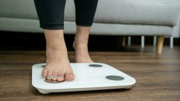 feet standing on electronic scales for weight control. Measurement instrument in kilogram for a diet control photo