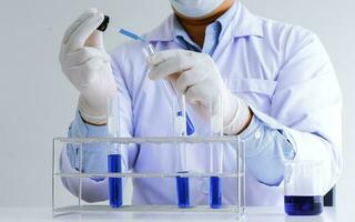 Science innovative Male medical or scientific laboratory researcher performs tests with blue liquid in laboratory. equipment science experiments technology Coronavirus Covid-19 vaccine research photo