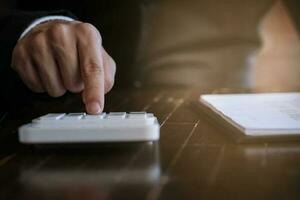 Businessman analyzing investment charts and pressing calculator buttons over documents. Accounting Concept. photo