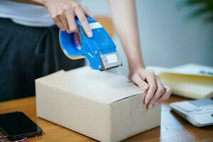 asiático mujer preparando paquete entrega caja Envío para compras en línea entrega correo Servicio personas y envío concepto foto