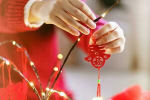 Asian Woman decorated house for Chinese New Year Celebrations. putting traditional pendant to the Chinese Lunar New Year for good luck. Chinese word means blessing photo