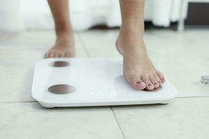 feet standing on electronic scales for weight control. Measurement instrument in kilogram for a diet control. photo