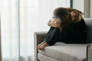 Sad woman thinking about problems sitting on a sofa upset girl feeling lonely and sad from bad relationship or Depressed woman disorder mental health. photo