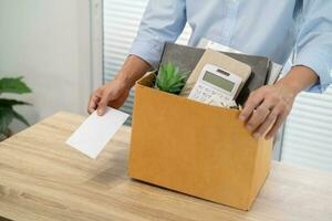 sending resignation letter to boss and Holding Stuff Resign Depress or carrying cardboard box by desk in office photo