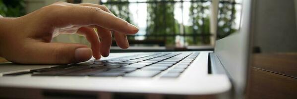 Working by using a laptop computer on wooden table. Hands typing on a keyboard. photo