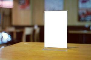 Mock up Menu frame standing on wood table in Bar restaurant cafe. space for text photo