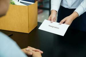 Business woman sending resignation letter to boss and Holding Stuff Resign Depress or carrying cardboard box by desk in office photo