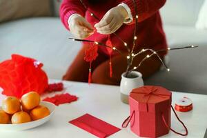 asiático mujer decorado casa para chino nuevo año celebraciones poniendo tradicional colgante a el chino lunar nuevo año para bueno suerte. chino palabra medio bendición foto