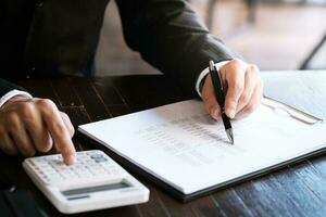 Businessman analyzing investment charts and pressing calculator buttons over documents. Accounting Concept. photo