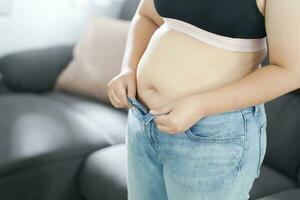 obeso mujer con grasa trastornado acerca de su barriga. exceso de peso mujer conmovedor su grasa barriga y querer a perder peso. grasa mujer con apretado ropa preocupado acerca de peso dieta estilo de vida concepto foto