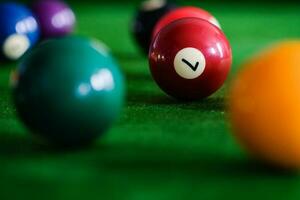 Man's hand and Cue arm playing snooker game or preparing aiming to shoot pool balls on a green billiard table. Colorful snooker balls on green frieze. photo