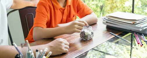 Asian father and son teaching son to Financial Literacy save money. Dad and children putting money to the money box. fatherhood. photo