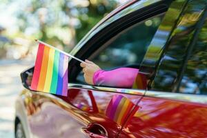 Happy Asian woman support LGBT pride parade in car. with Rainbow of LGBTQ or LGBTQIA. photo