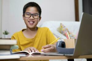 Young boy using computer and mobile device studying online. photo