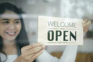 Close up of woman hands holding sign now we are open support local business. photo