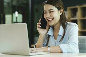 Smiling businesswoman talking on smartphone while waiting client in office photo