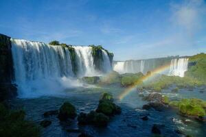 Iguazu Falls on the border between Argentina and Brazil with beautiful rainbows and lots of vegetation and lots of water falling down them photo