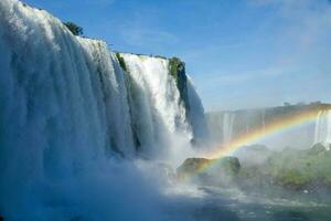 Iguazu Falls on the border between Argentina and Brazil with beautiful rainbows and lots of vegetation and lots of water falling down them photo