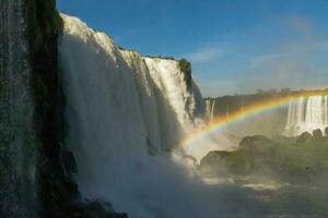 Iguazu Falls on the border between Argentina and Brazil with beautiful rainbows and lots of vegetation and lots of water falling down them photo