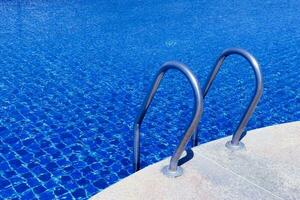 nadando piscina con escalera a hotel cerca arriba, escalera inoxidable pasamanos para descendencia dentro nadando piscina. foto