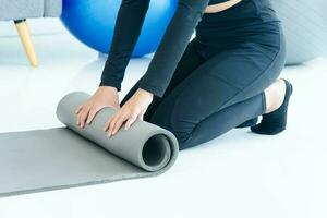 Healthy lifestyle concept. Close up healthy woman preparing yoga mat before workout in the living room photo