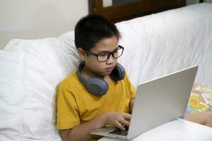 Young boy using computer and mobile device studying online. photo