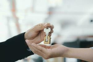 Real estate agent  holding key with house shaped keychain. photo