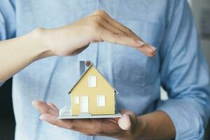 Businessman hand hold the house model saving small house. photo