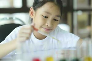 Little child with learning class in school laboratory using microscope photo