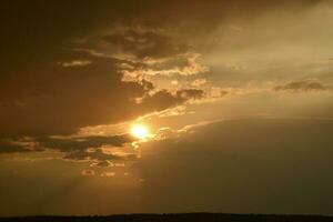 Stormy sunset. Yellow-blue clouds and the setting sun. photo