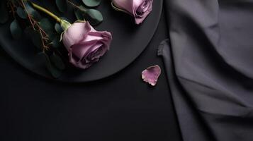 A black plate with a black piece of cloth top view picture with light purple roses on it. photo