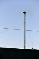 Metal silver pipe with smoke on the background of the sky. A long chimney. photo