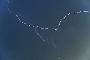 Blue lightning in a dark stormy sky. Stormy skies in summer. A storm with lightning. photo