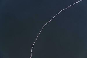 Blue lightning in a dark stormy sky. Stormy skies in summer. A storm with lightning. photo