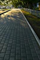 Summer city street in the setting sun. People walking away into the distance. City summer road and sidewalk. photo