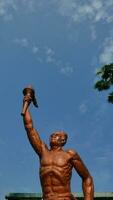 Surakarta, Indonesia, 20th June 2023, Statue of spirit of sport in a form of man holding torch against blue sky, Patung obor manahan located at the Manahan stadium Surakarta photo