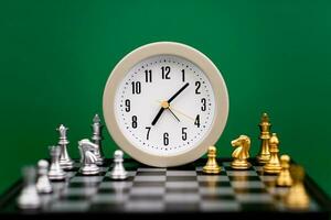 alarm clock on chess table time strategy plan work with time green backdrop Working with time. Be on time. Keep time. Value time concept. photo